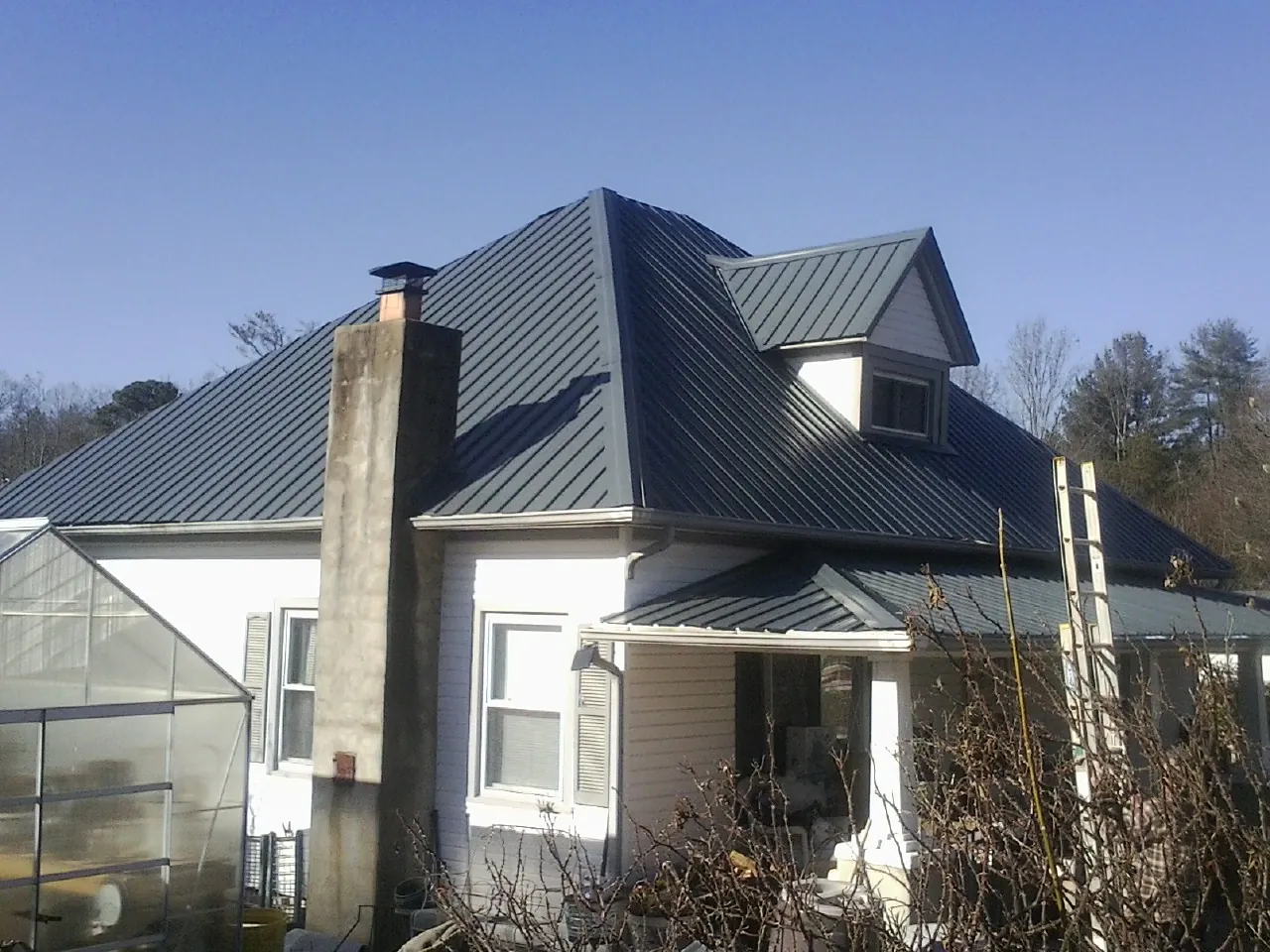 Dark blue standing seam metal roof on a white farmhouse with dormer — Slate & Tile Roof Repair by Roofing Brothers in Evergreen Park
