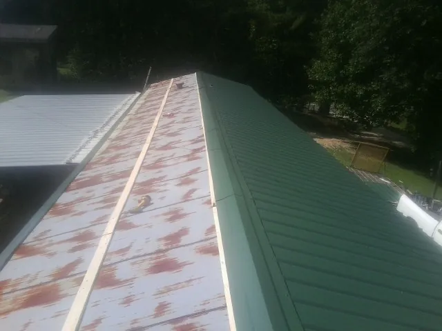 Old rusted panels beside newly installed green metal roofing — Wind Damage Roof Repair by Roofing Brothers in Evergreen Park