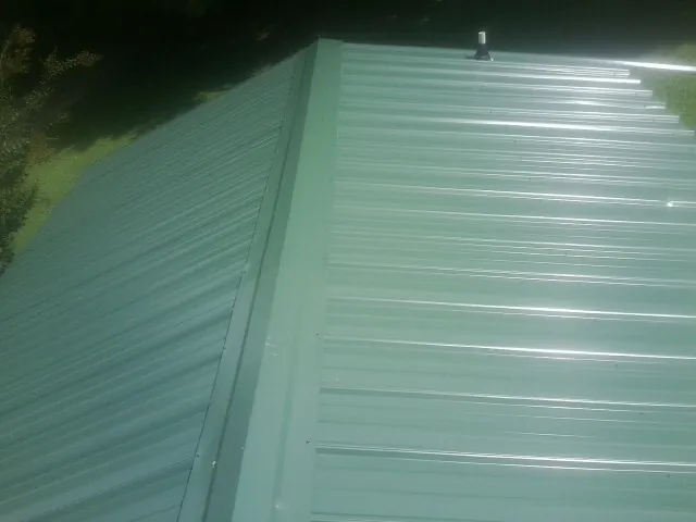 New green metal panels meeting at the ridge of a roof — Flat Roof Repair work by our crew in Evergreen Park
