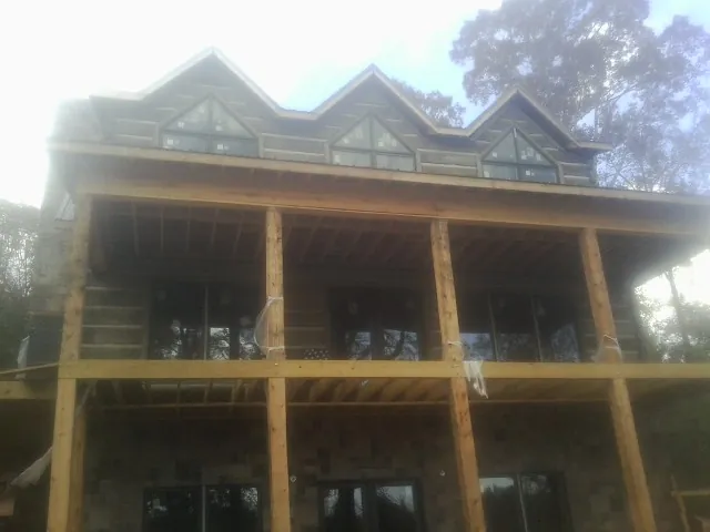 Dormers and porch framing on a large log home under construction — Roof Coating work by our crew in Evergreen Park