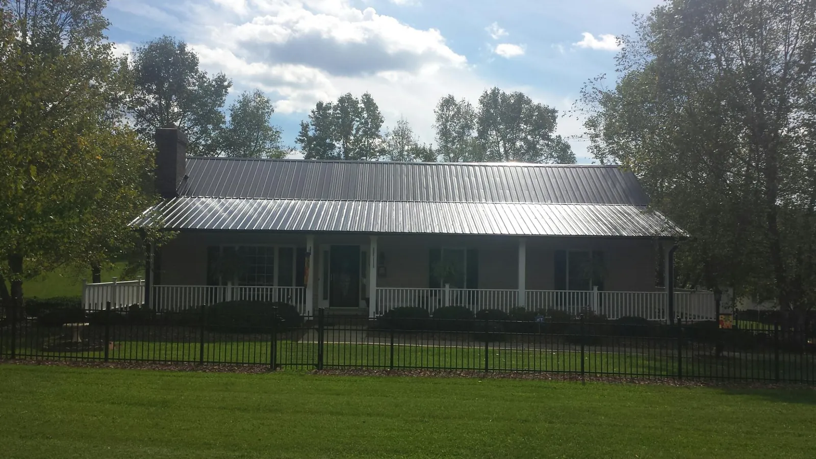 Gray metal roof on a brick ranch with a full width front porch — Gutter Guard Installation work by our crew in Evergreen Park