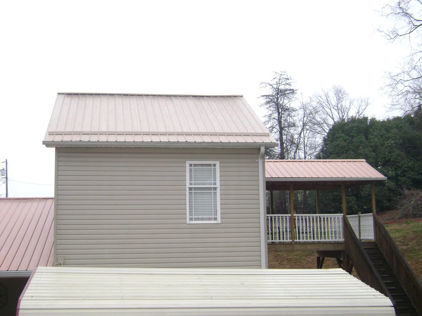 Tan metal roofs on a two story addition and attached porch, from a Roof Replacement job in Evergreen Park