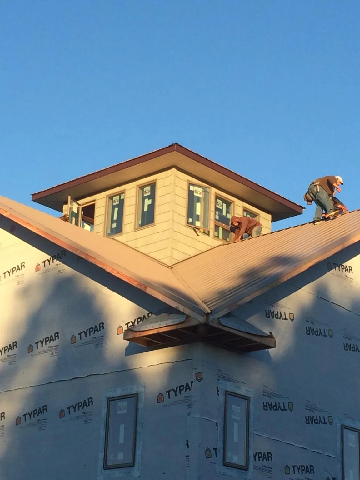 Roofers working around a rooftop cupola on a new metal roof at sunset — Roof Waterproofing in Evergreen Park by Roofing Brothers
